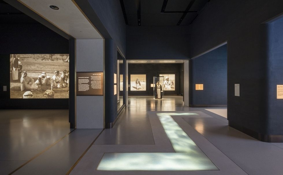 Museum hallway with historical photos and information panels on dimly lit walls at Zayed National Museum.