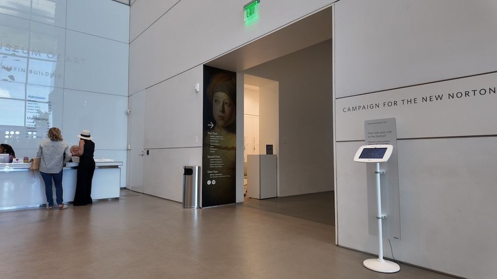 Museum lobby with people at the information desk and "Campaign for the New Norton" sign.
