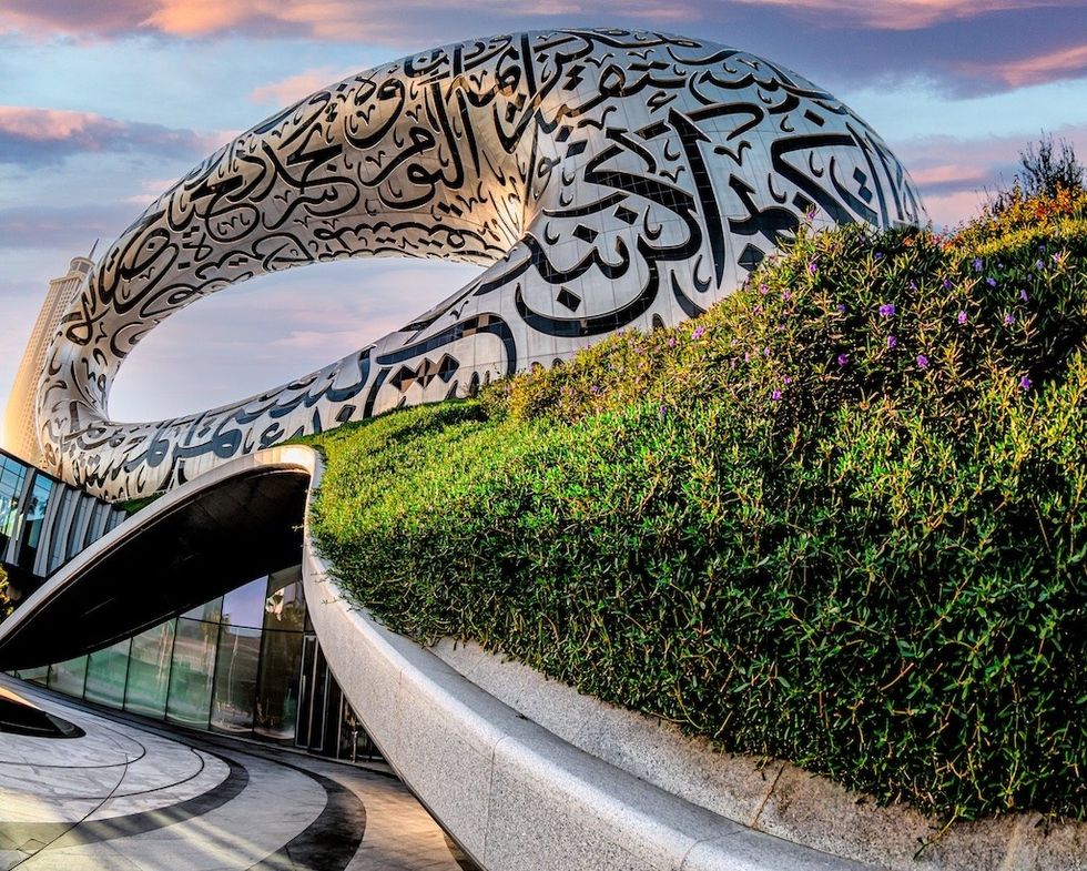 Museum of the Future in Dubai, a futuristic building with Arabic script and greenery under a colourful sky.