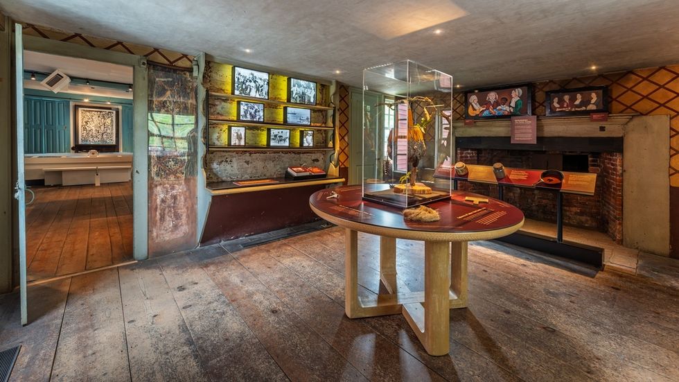 Museum room at the Edward W. Kane & Martha J. Wallace Center for Black History, with artifacts in a glass case on a round table, wooden floors, and wall displays.
