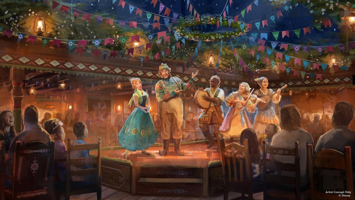Musicians perform on a festive, decorated stage in front of an audience on the Disney Believe