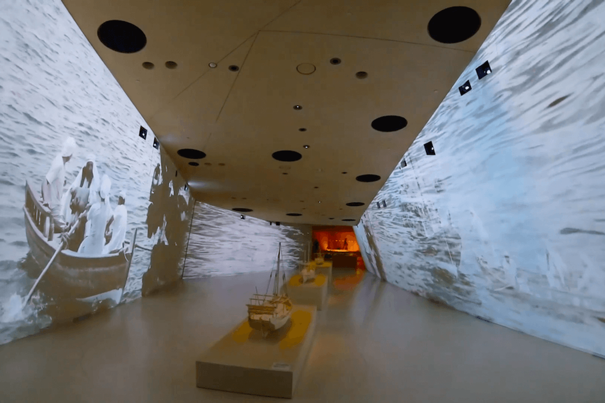 National Museum of Qatar hallway with boat projection on walls and model ships on display.