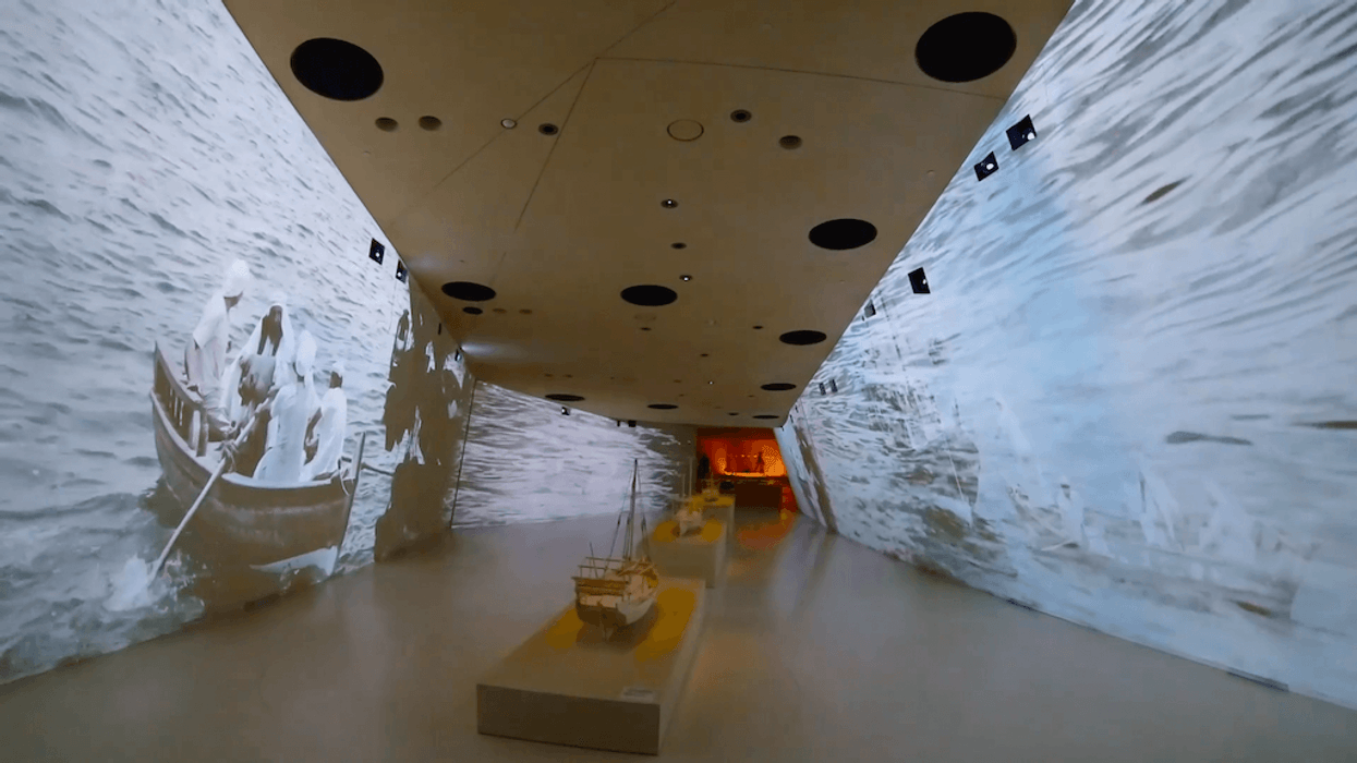 National Museum of Qatar hallway with boat projection on walls and model ships on display.