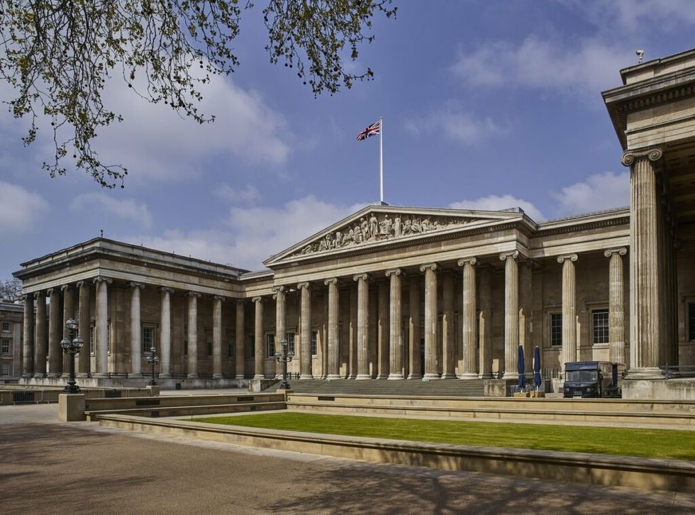 Neoclassical British Museum building with columns, British flag on top; overcast sky background.