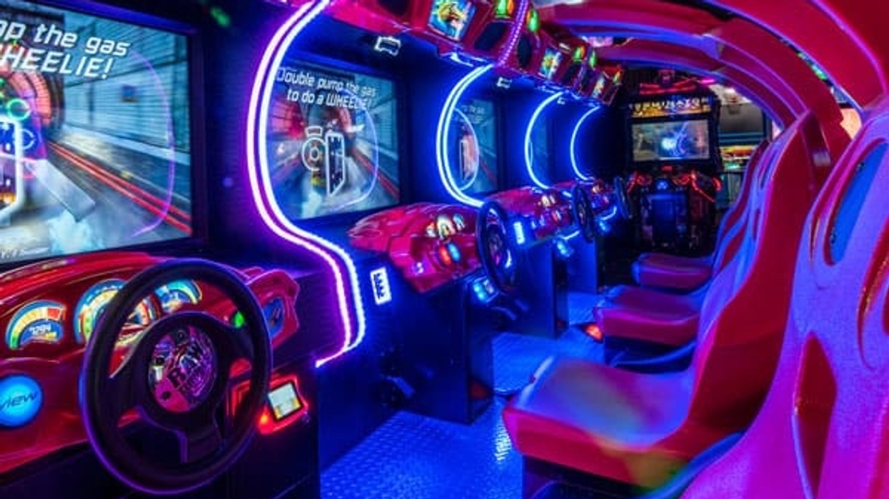 Neon-lit arcade racing game machines with red seats and steering wheels.