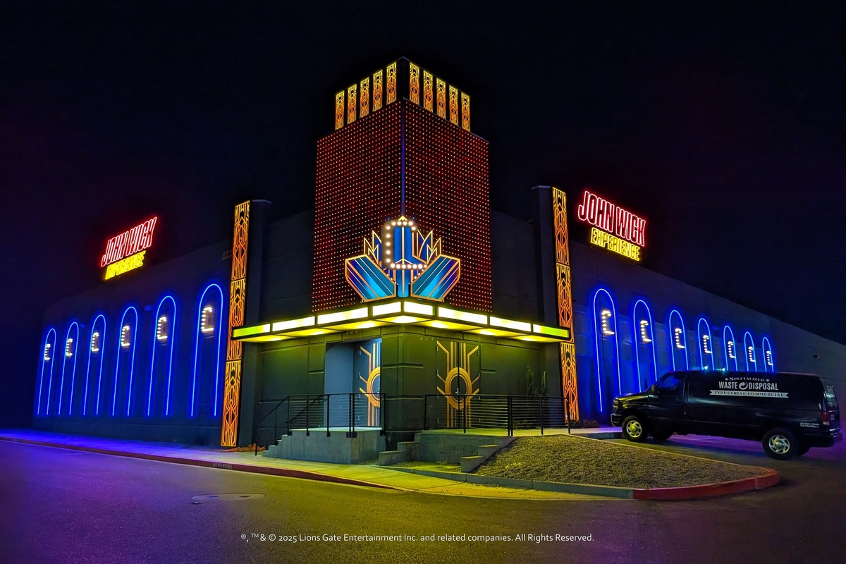 Neon-lit building with "John Wick Experience" signs at night.