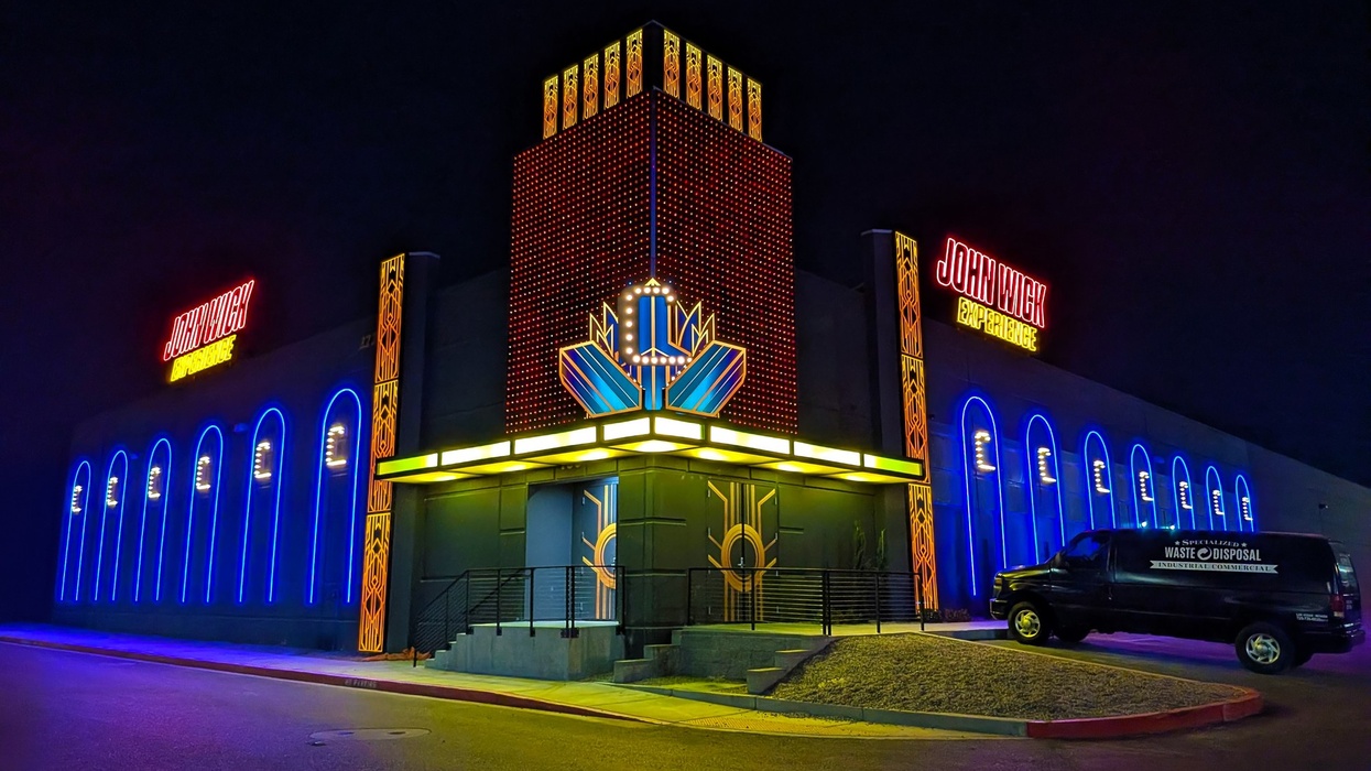Neon-lit building with "John Wick Experience" signs at night.