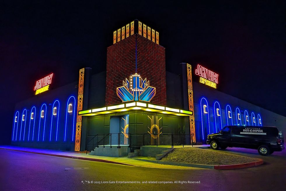 Neon-lit "John Wick Experience" building at night with van outside.