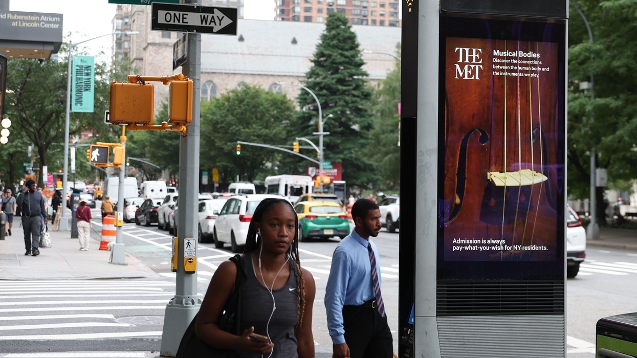 New York City street with pedestrians and a Met Museum ad featuring a cello.