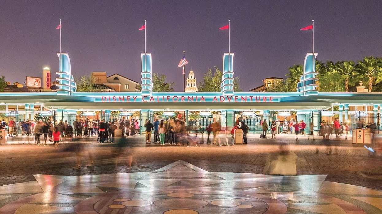 Night view of Disney California Adventure entrance with blurred crowds.