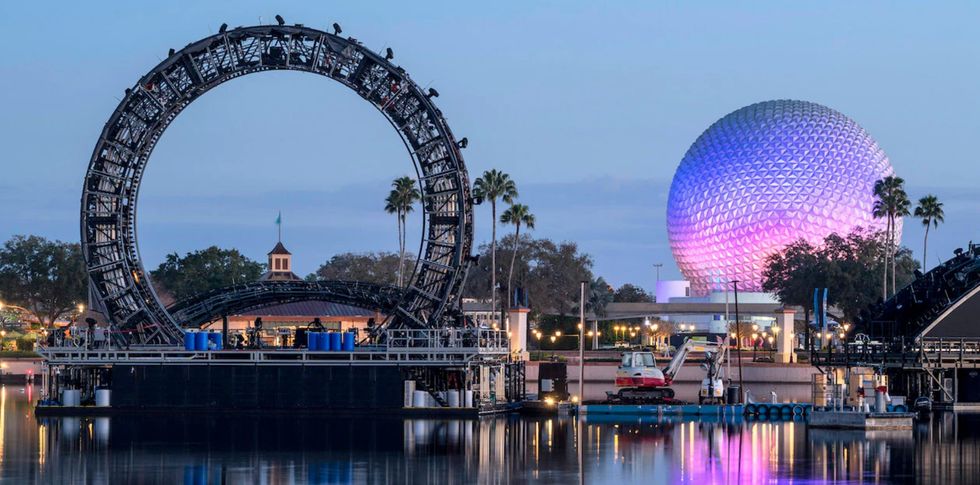 Night view of Epcot with glowing dome and circular stage structure on water.