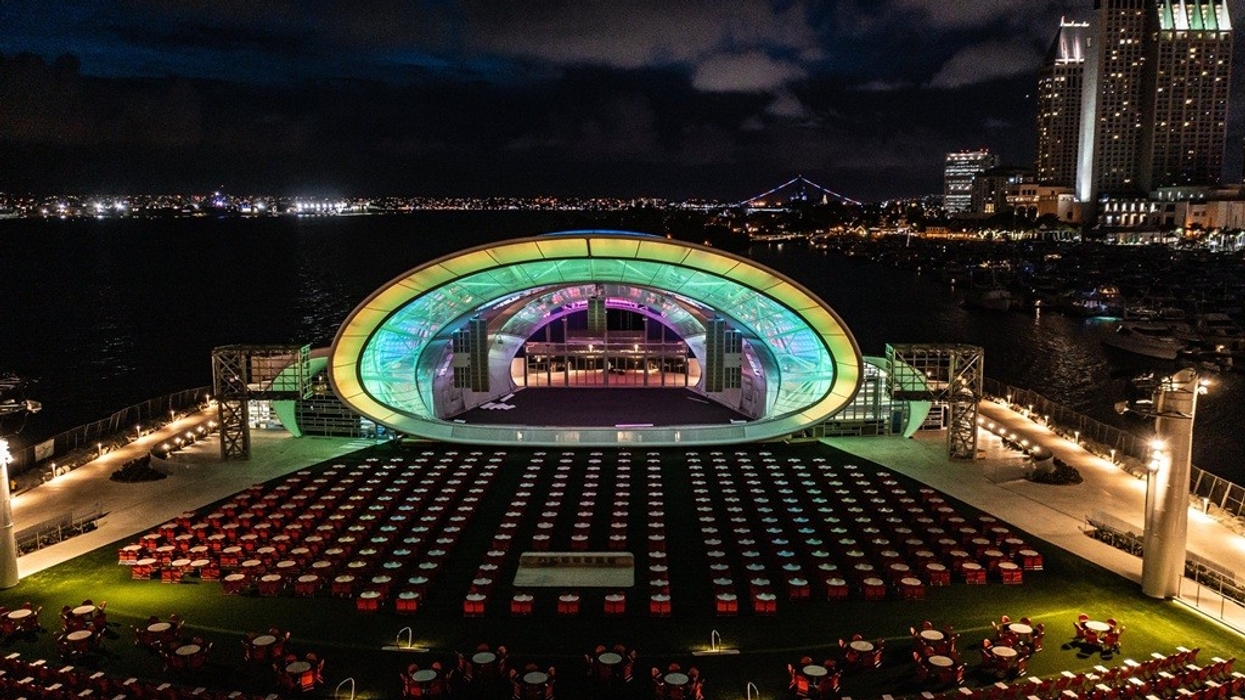 Night view of illuminated open-air stage with colorful lights and arranged seating by the bay.