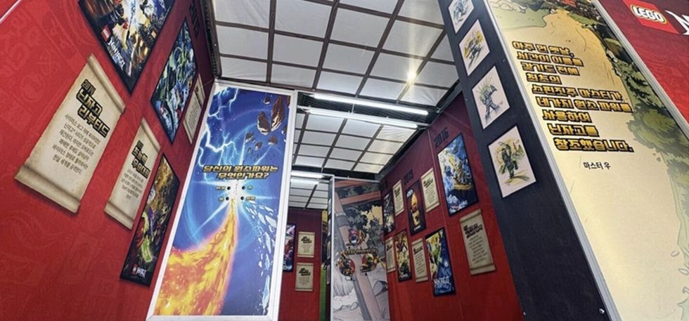 Ninjago exhibit designed by Katapult, with LEGO posters and art on red walls, featuring vibrant designs and text.