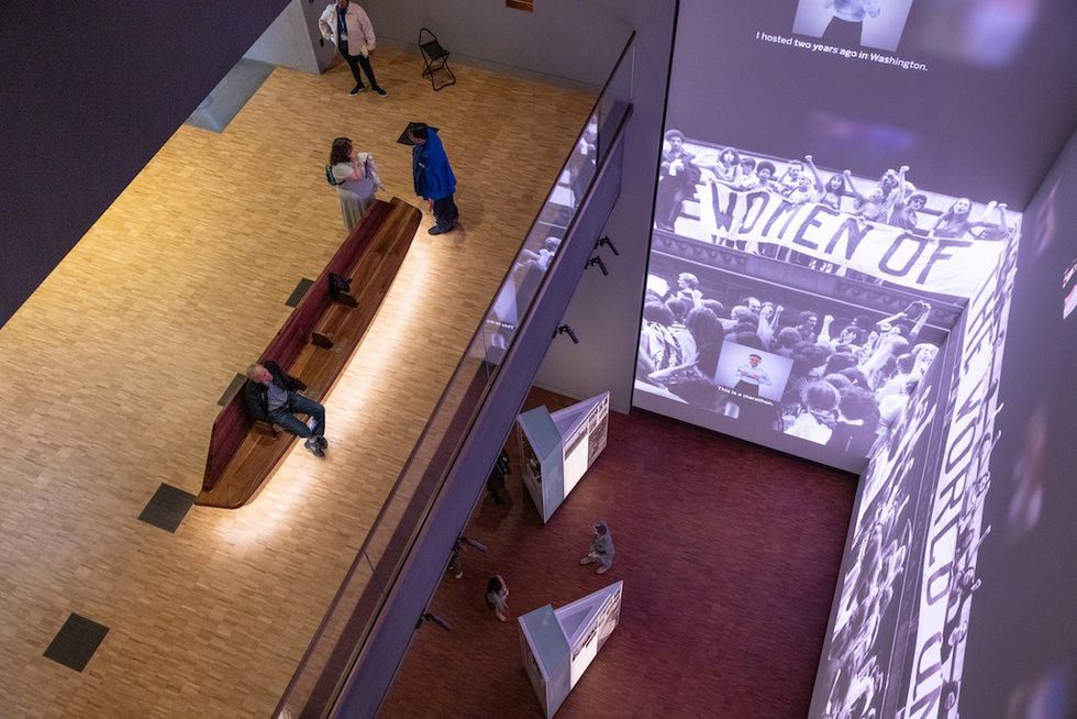 Obama Presidential Center Museum interior with large wall projections and people walking on wooden floors.