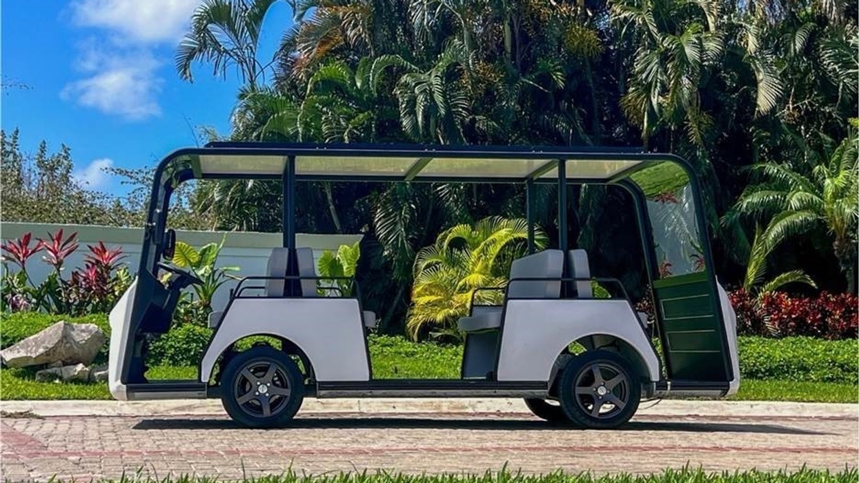 Open-air golf cart on path, surrounded by lush tropical plants and trees.