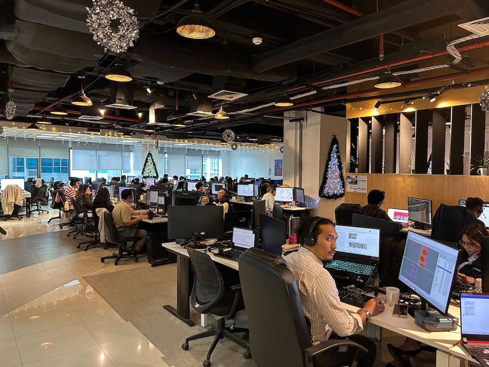 Open-plan office with festive decorations and employees working at computers.