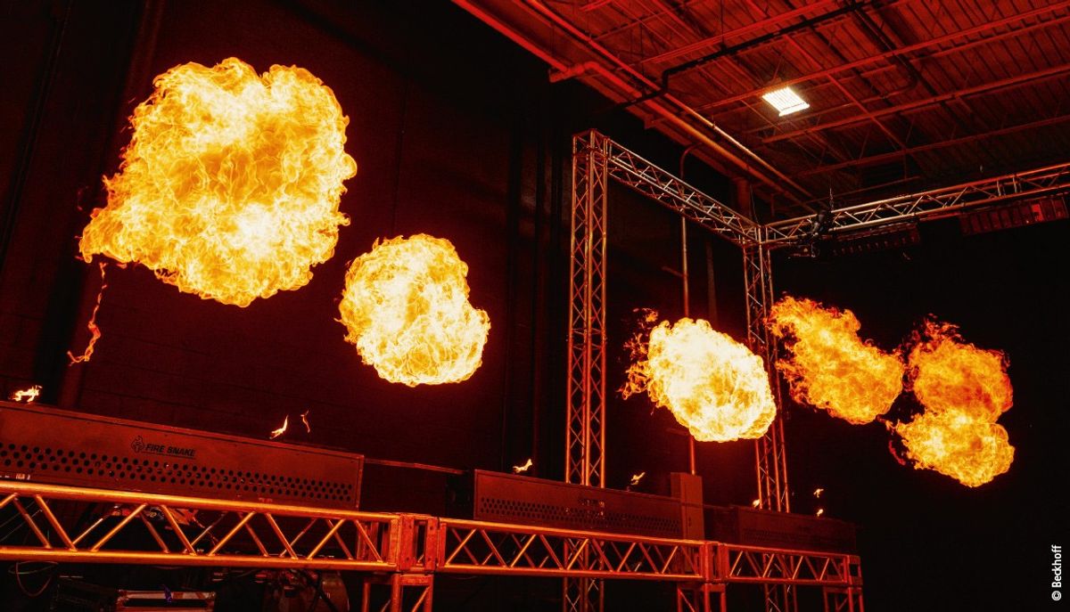 Orange fireballs in a dark room with metal stage structures.