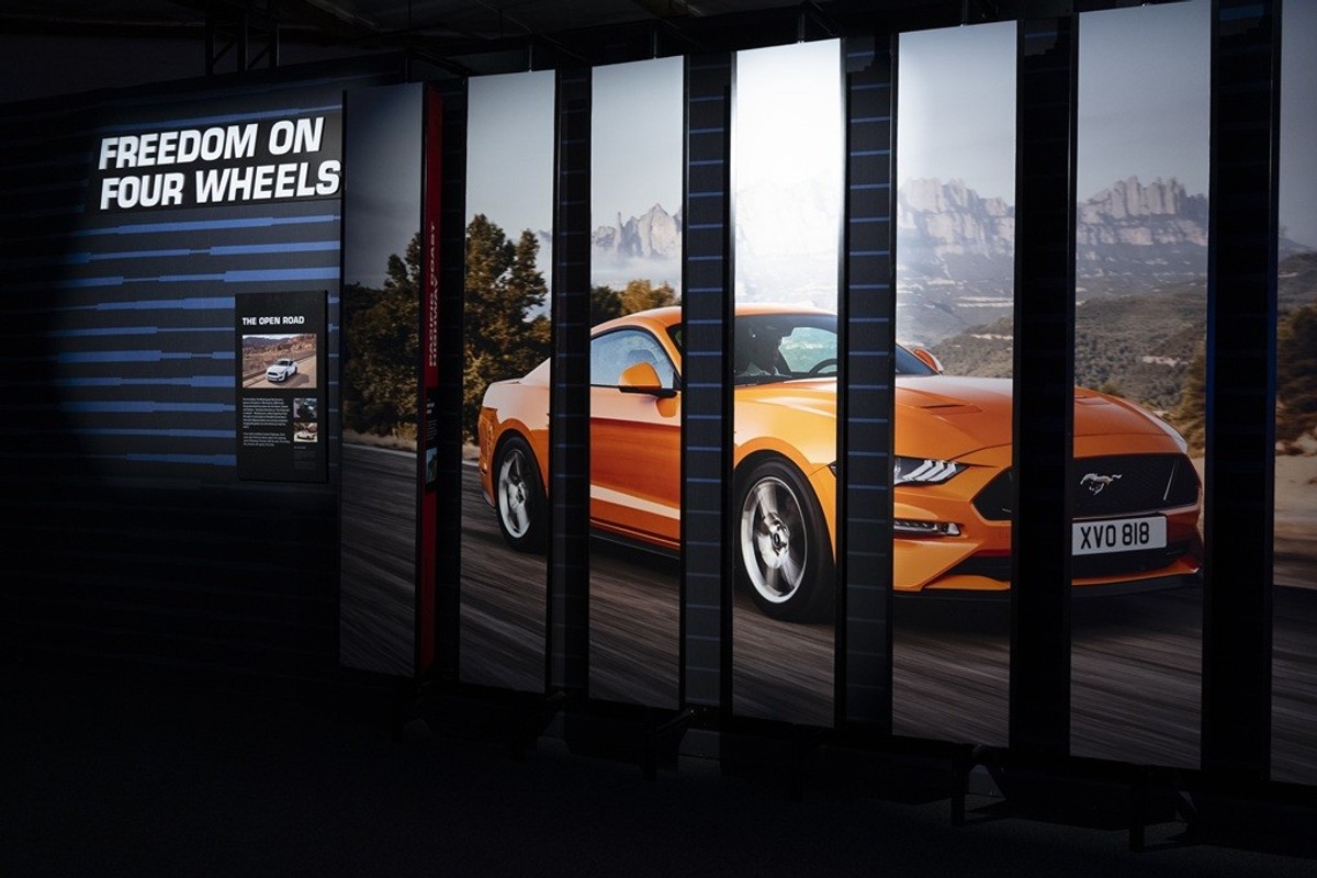Orange sports car display with "Freedom on Four Wheels" text behind.