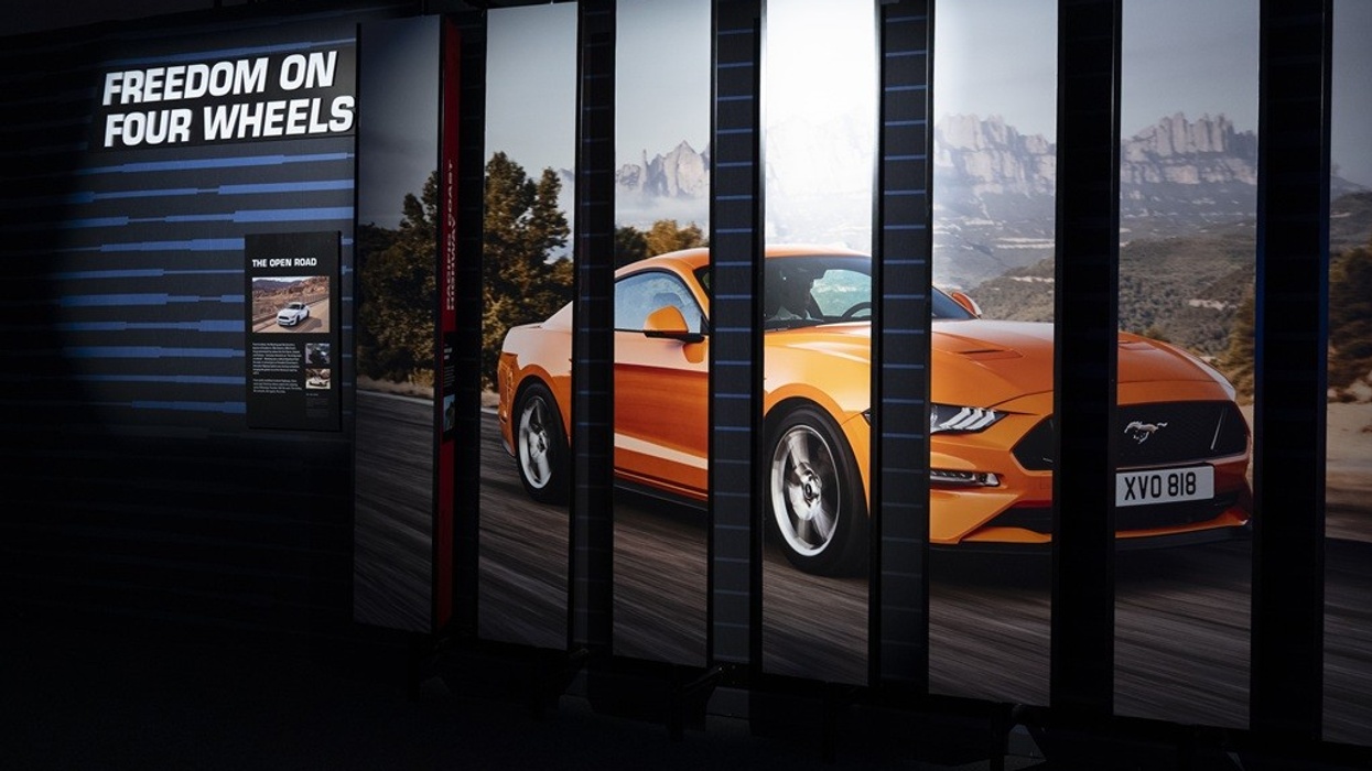 Orange sports car display with "Freedom on Four Wheels" text behind.