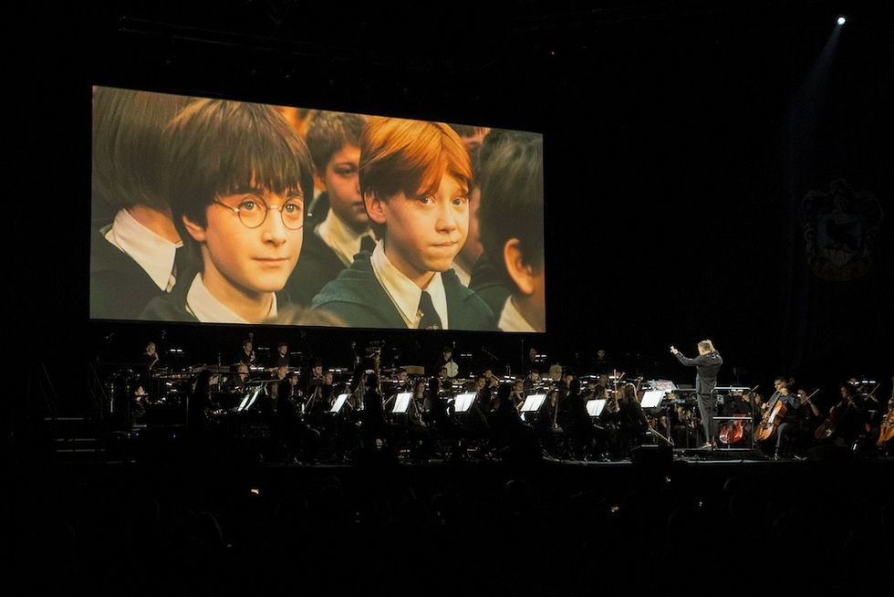 Orchestra performs with a large movie scene projected in the background.