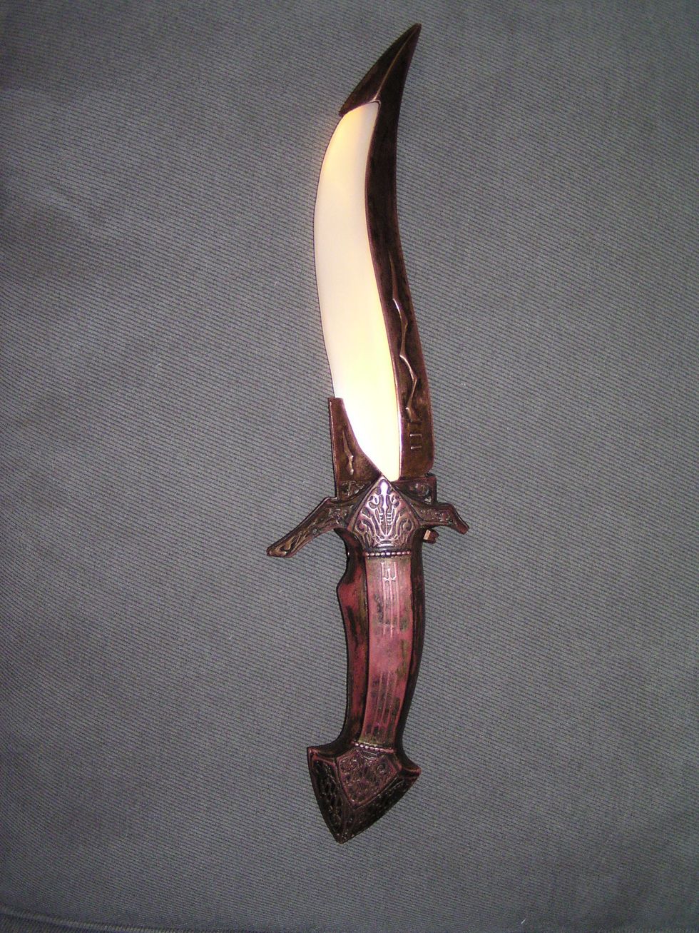 Ornate dagger with a curved blade and intricately detailed hilt on a gray background.