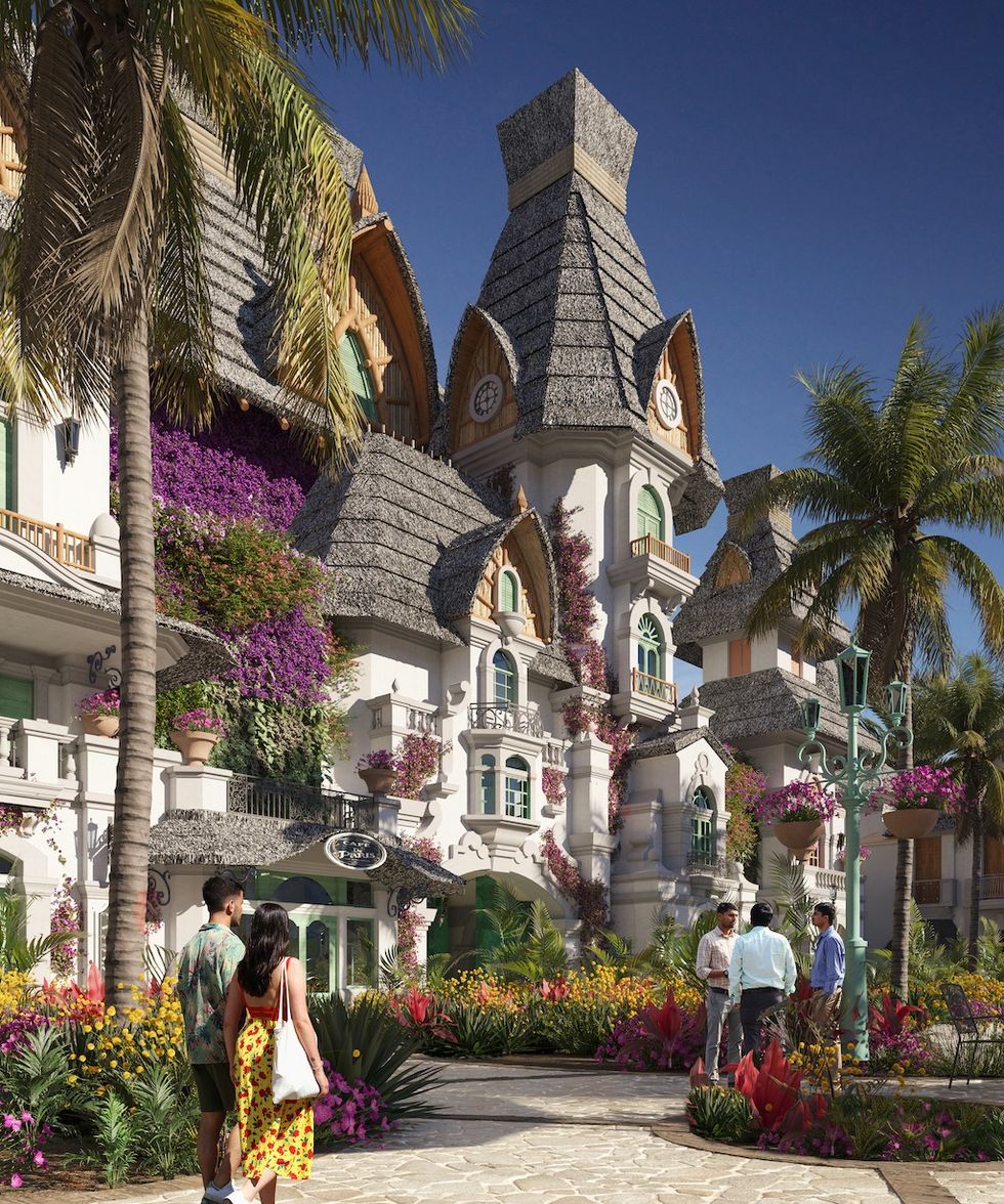 Ornate, fairy-tale style building with lush gardens and palm trees under a clear blue sky.