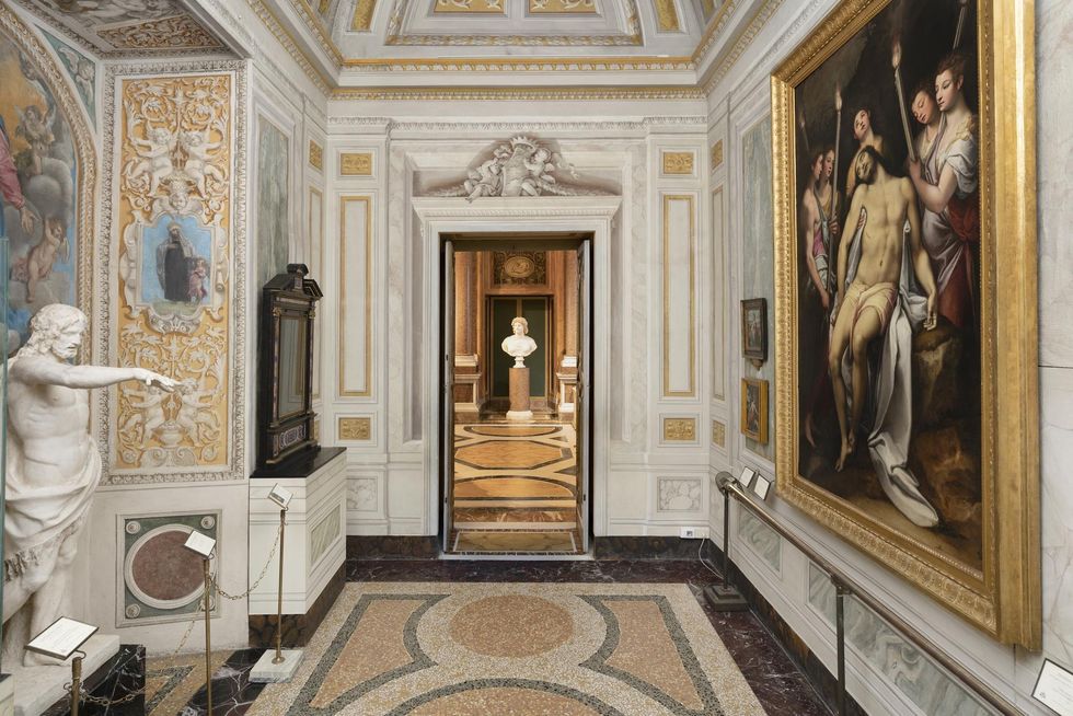 Ornate gallery room at Galleria Borghese with statues, paintings, and intricate wall designs.