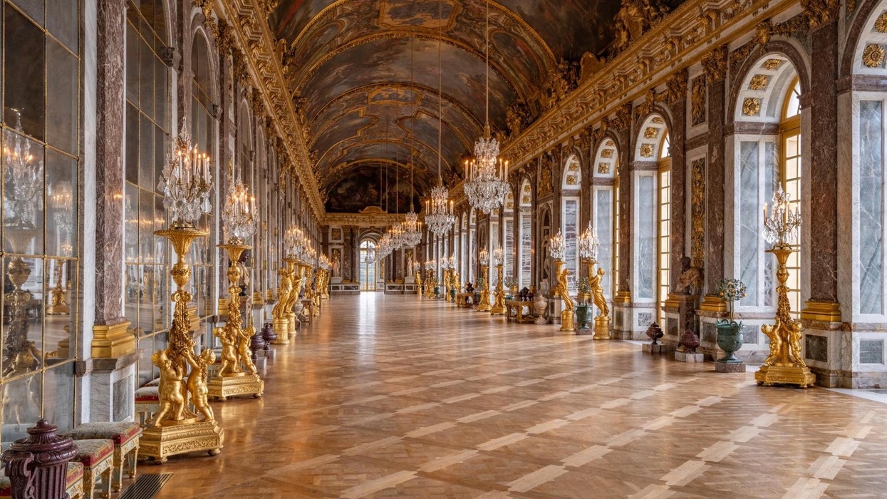 Ornate hall with chandeliers, mirrored walls, and arched windows.