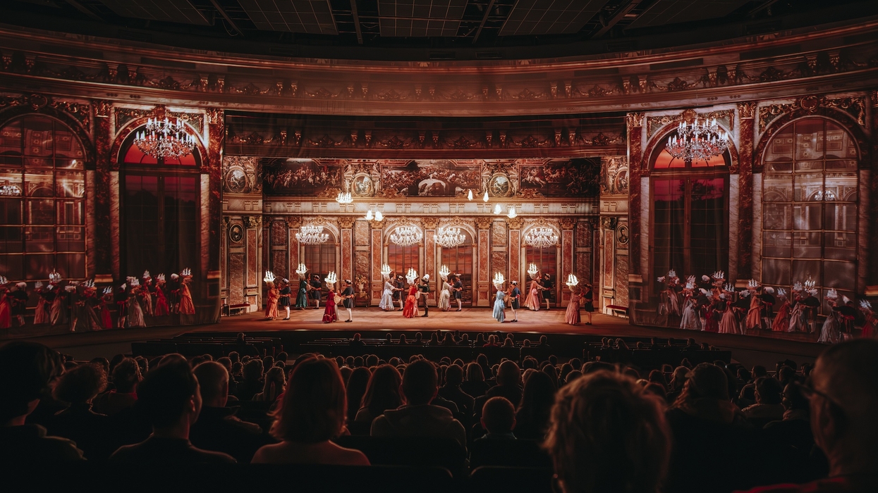 Ornate theater scene from Le Dernier Panache at Puy du Fou with actors in period costumes, viewed by an audience.