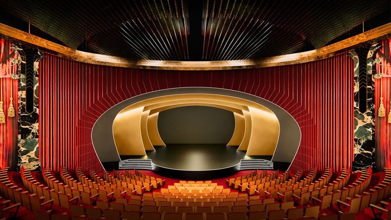 Ornate theater with red seats, gold accents, and an elliptical, modern stage design at Wynn Al Marjan Island
