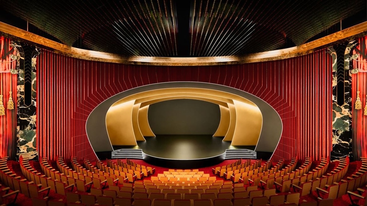 Ornate theater with red seats, gold accents, and an elliptical, modern stage design at Wynn Al Marjan Island