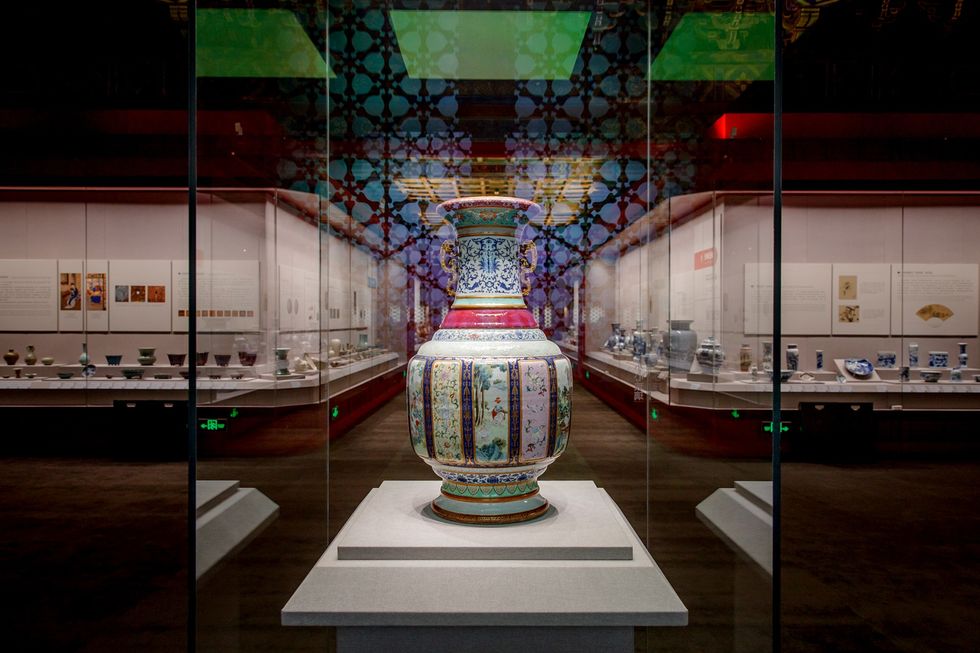 Ornate vase displayed in a glass case in a museum, surrounded by other artifacts.