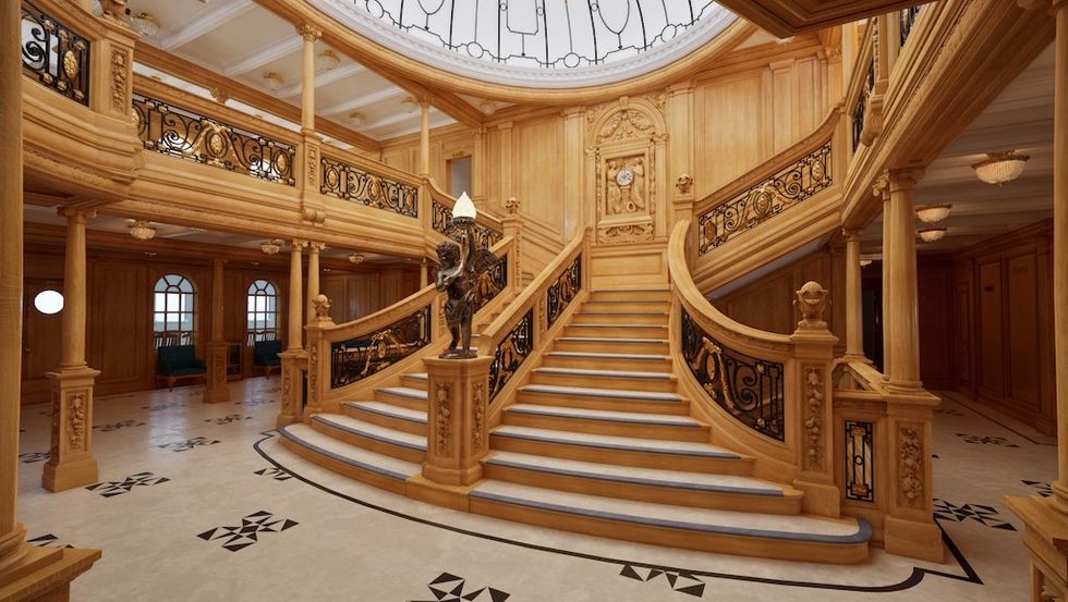 Ornate wooden staircase with black railings and a decorative clock above.