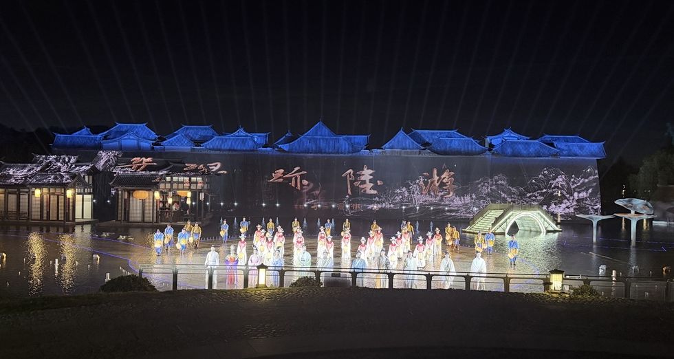 Outdoor night performance, 'The Wonders of Lu You', with traditional costumes, projected backdrop, and decorative bridge.