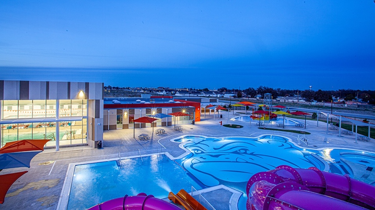 Outdoor water park with colorful slides and large pool featuring a bulldog design at dusk.
