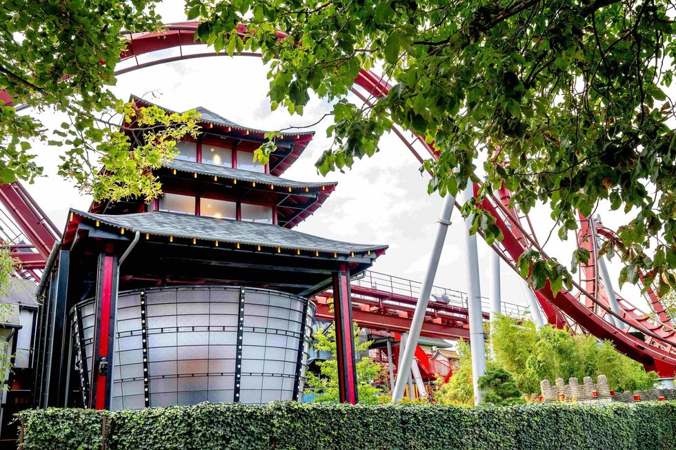 Pagoda and roller coaster surrounded by green trees and foliage at Tivoli Gardens