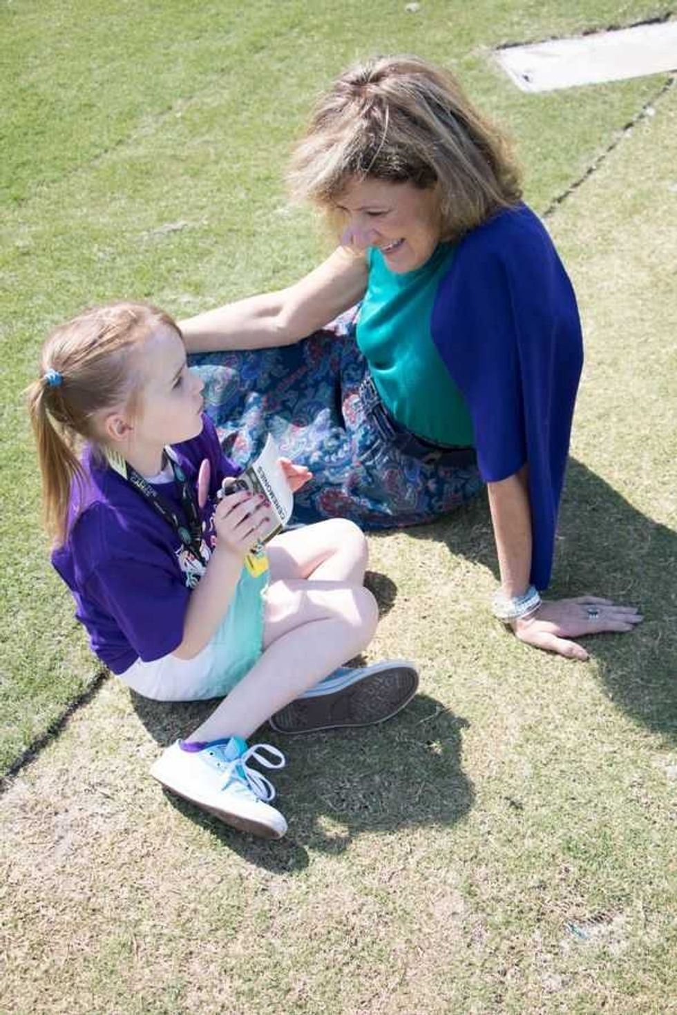 Pam Landwirth sitting on the ground chatting with a young girl at GKTW