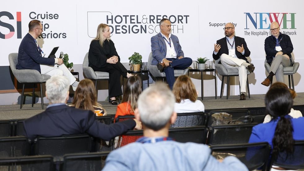 Panel discussion at a hotel design conference with five speakers and audience.