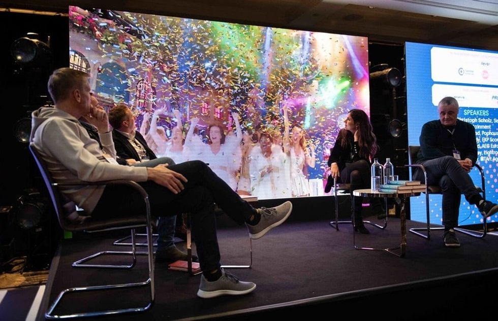 Panel discussion with a colorful screen backdrop and confetti visuals on stage.