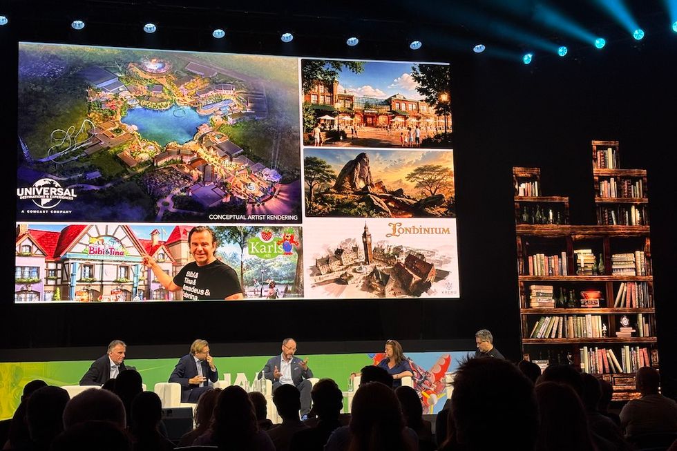 Panel discussion with theme park concepts on screen and audience watching.