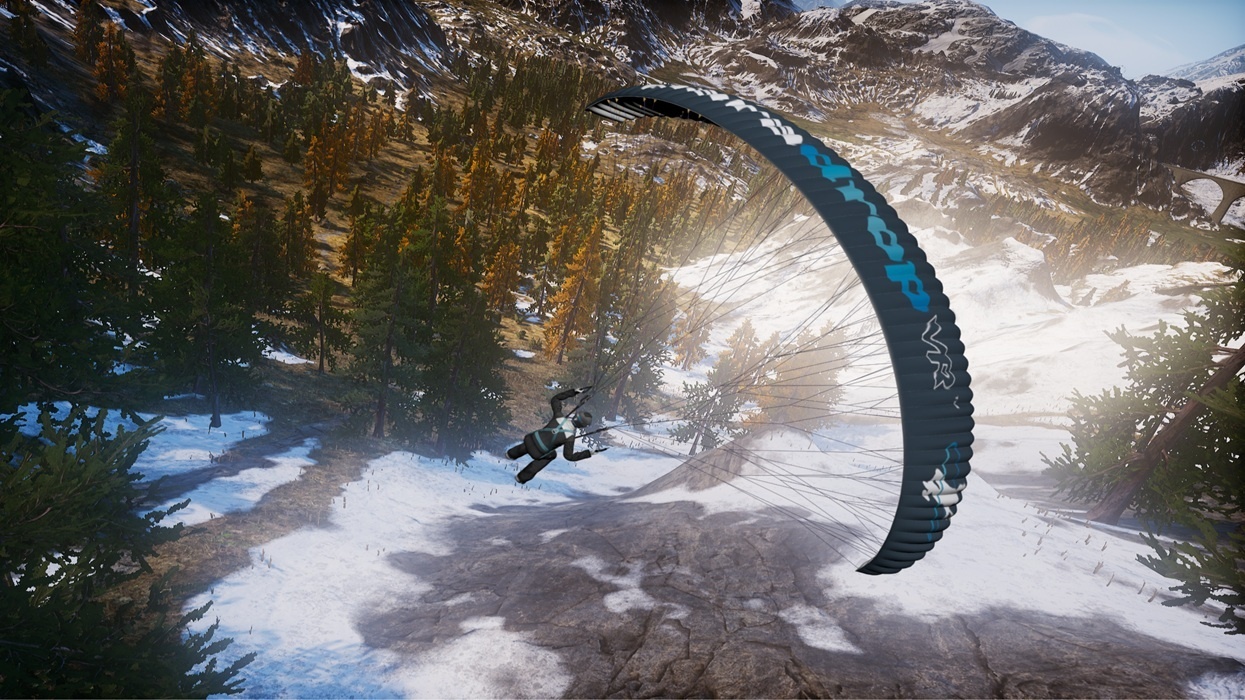 Paraglider soaring above snowy and forested mountain landscape.