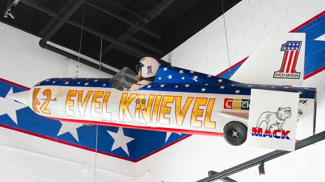 Patriotic-themed rocket bike display with "Evel Knievel" text, suspended indoors.