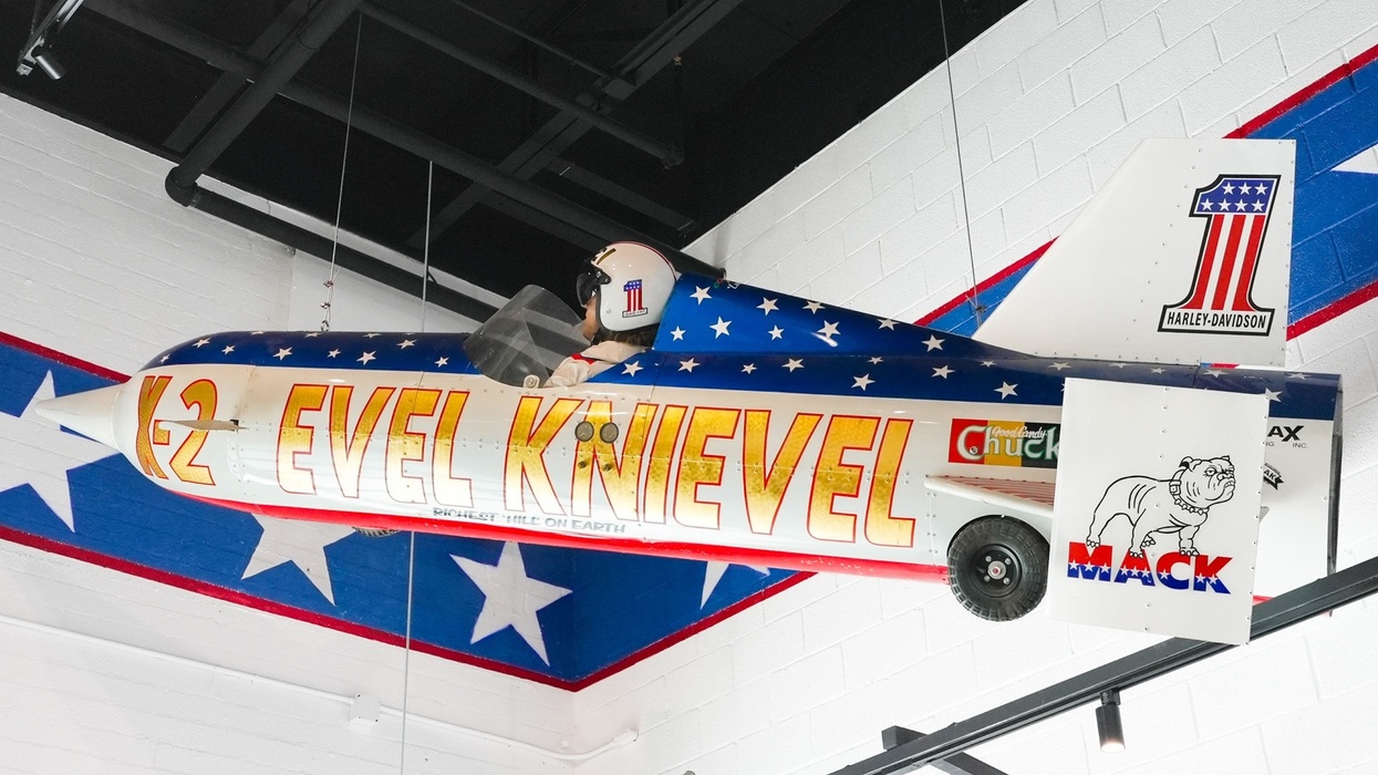 Patriotic-themed rocket bike display with "Evel Knievel" text, suspended indoors.