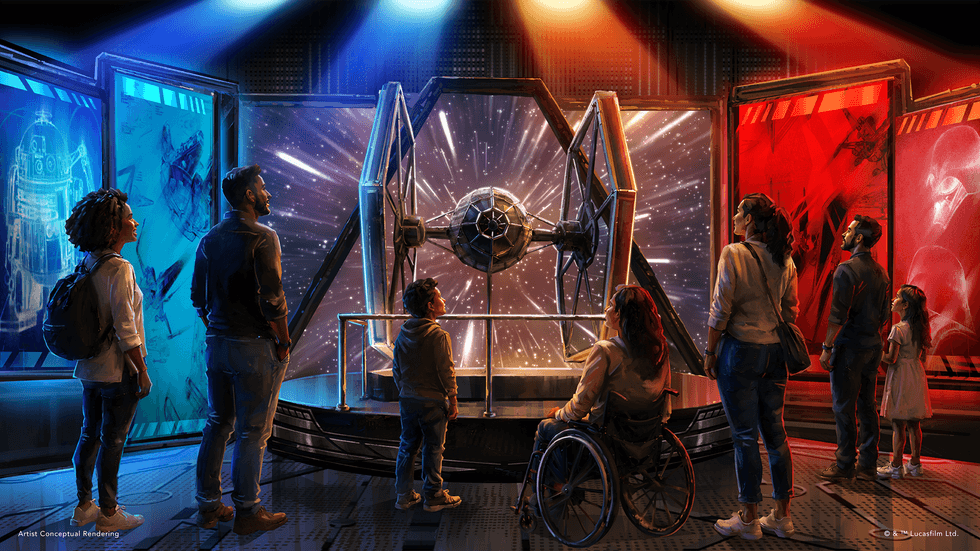 People admire a TIE fighter in a colorful Star Wars exhibit.