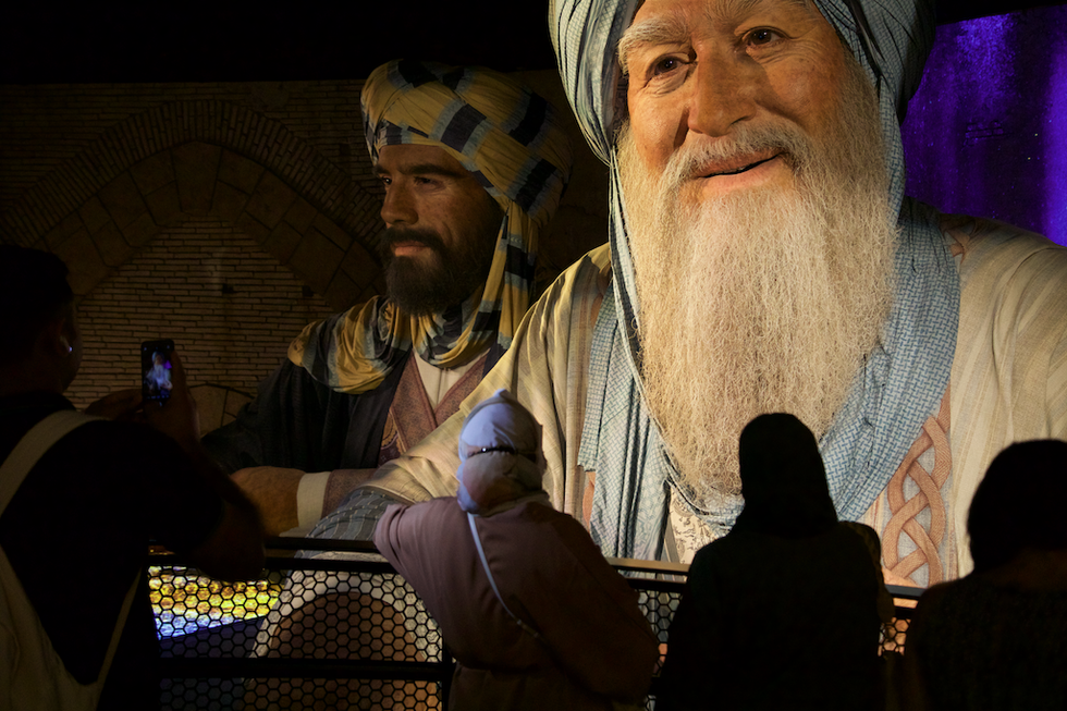 People admire an illuminated display of 'bigature' historical figures in traditional attire at Alif \u2013 The Mobility Pavilion