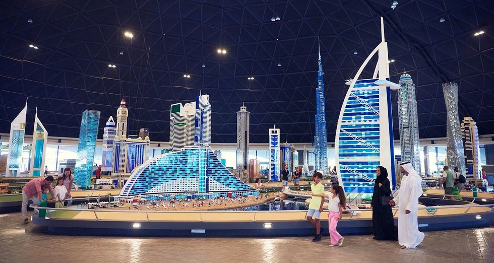 People admire detailed Lego models of skyscrapers under a dome at Legoland Dubai