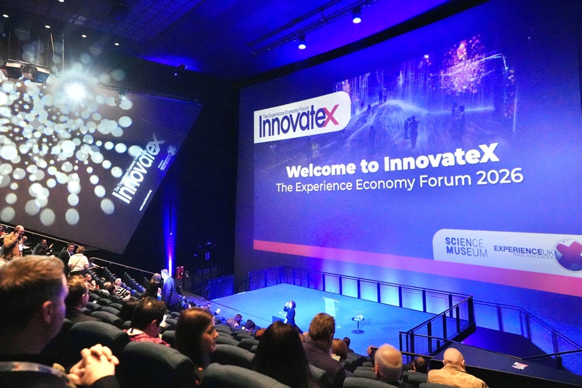 People attending InnovateX 2026 at a large auditorium with presentations on screen.