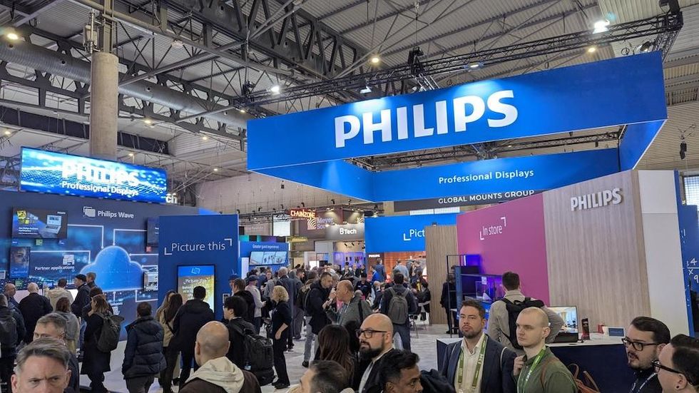 People browsing in a large exhibition hall with Philips display booths.