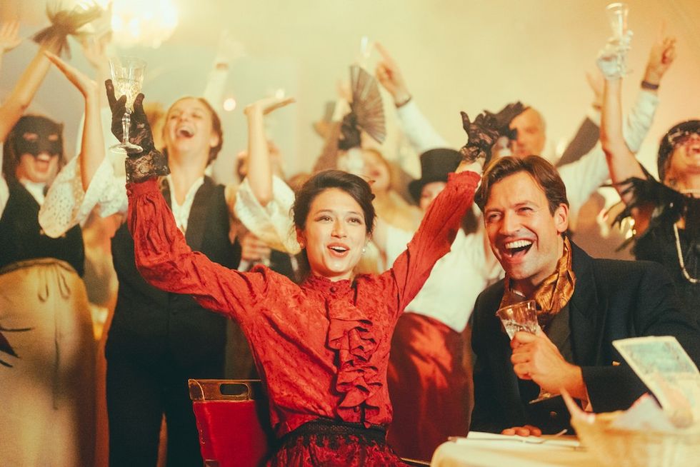 People celebrating at a lively costume party with drinks raised in cheer.