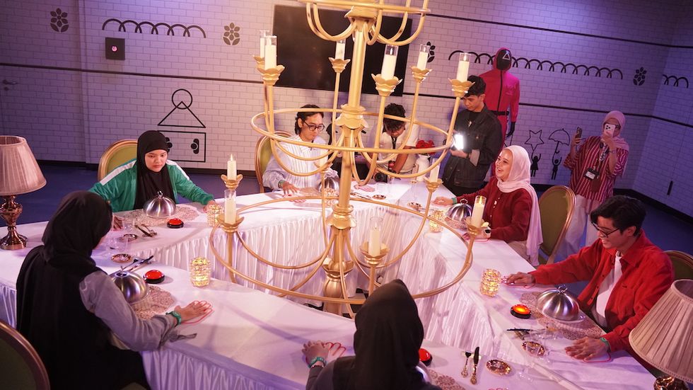 People dining at a table with a large chandelier centerpiece.